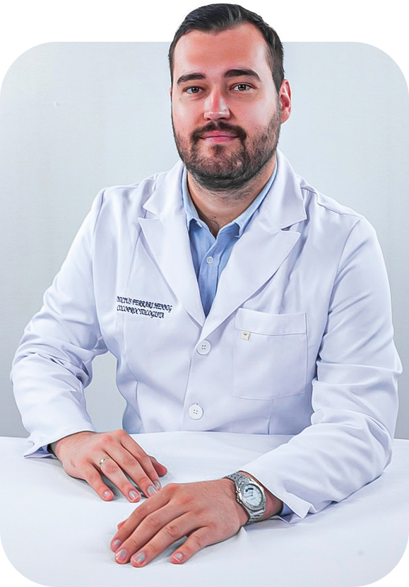 Foto do Dr. Vinicius Hennig Médico Coloproctologista profissional sentado com as mãos sobre uma mesa